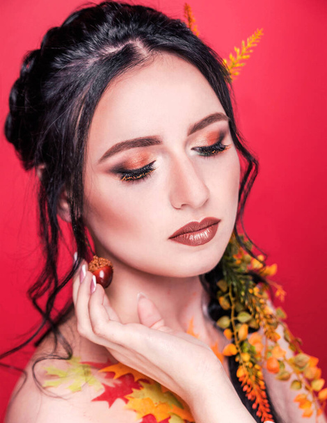 Moderní podzimní make-up. Módní modelka krásy. Detailní portrét izolovaný na červeném pozadí. Svislá fotografie - Fotografie, Obrázek