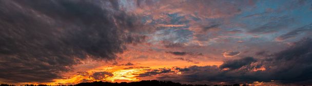 Красочная и драматическая панорама неба на фоне заката. яркие и контрастные грозовые облака - Фото, изображение