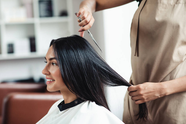 jong brunette vrouw getting short haircut bij kappers, close up - Foto, afbeelding
