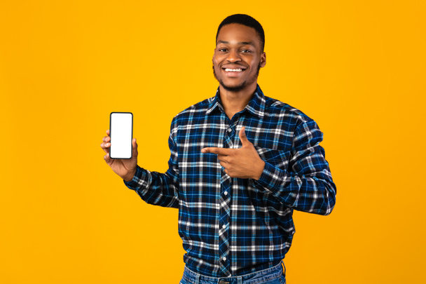 Veselý africký muž ukazuje smartphone prázdné obrazovky, žluté pozadí, Mockup - Fotografie, Obrázek