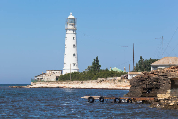 Wooden pier for excursion boats against the background of the Tarkhankut lighthouse, Crimea - Fotó, kép