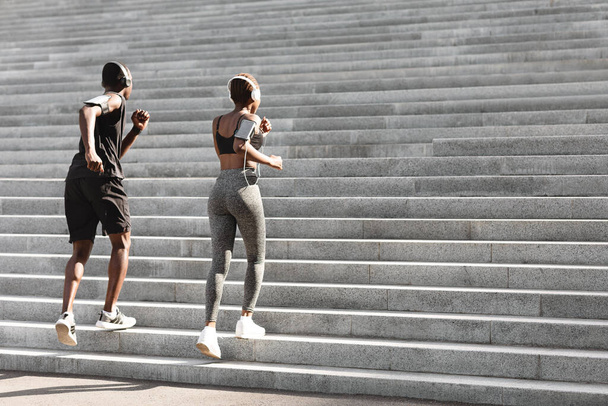 Спортивні чорні захисники біжать по сходах у міському парку - Фото, зображення