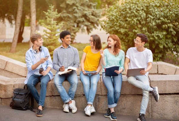 Étudiants du secondaire apprenant à faire leurs devoirs ensemble assis à l'extérieur - Photo, image
