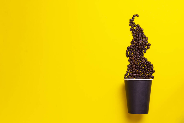 Koffiebonen met thermo cup op een gele achtergrond - Foto, afbeelding
