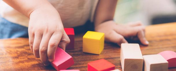 Closeup hand of boy playing wooden block toy on table for creative with enjoy, happy child learn skill for activity puzzle and creativity for game on desk at home, education concept, banner website. - Foto, immagini