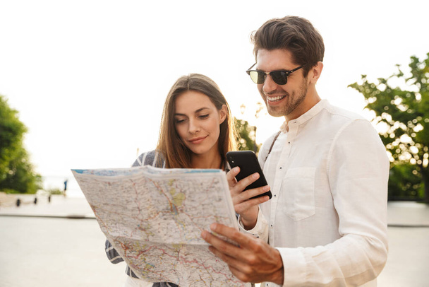 Couple of travelers with map of town deciding where to go - Foto, imagen