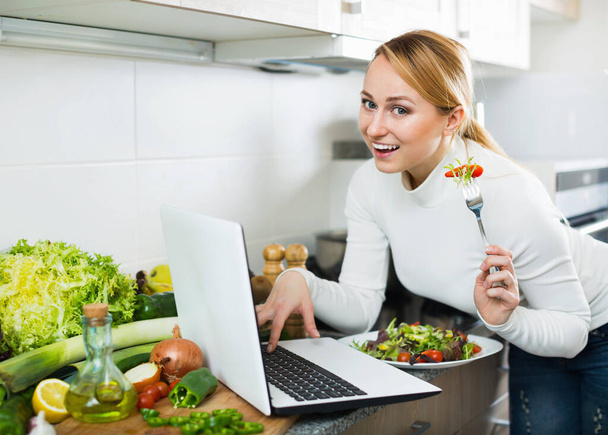 Pretty freelancer having lunch and working in kitchen top - Photo, image