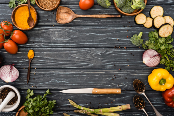 vista superior de verduras frescas de colores, especias cerca de cuchillo y espátula en la superficie de madera - Foto, Imagen