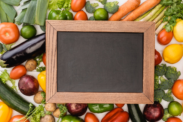 top view of fresh ripe vegetables and fruits near empty chalkboard - 写真・画像