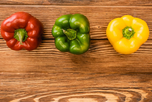 top view of colorful ripe bell peppers on wooden table - Photo, Image