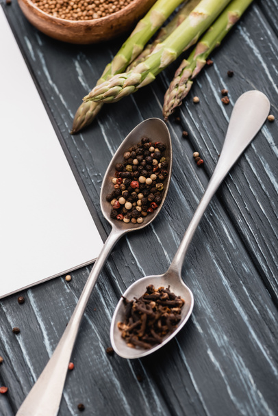 spices in spoons near asparagus on wooden surface - Fotoğraf, Görsel