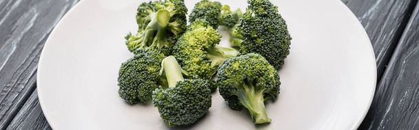 fresh green broccoli on white plate on wooden surface, panoramic shot - Photo, Image