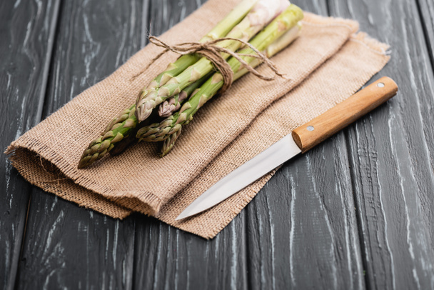 fresh green asparagus on burlap with knife on wooden surface - Fotoğraf, Görsel