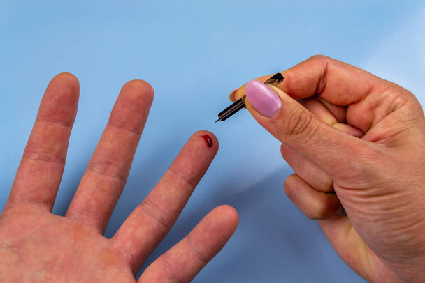 Eine Frau sticht sich mit einem Vertikutierer in den Finger. Weltdiabetestag - Foto, Bild