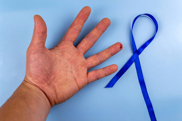 Мужская рука с каплей крови на пальце и признаком диабета. Всемирный день борьбы с диабетом - Фото, изображение