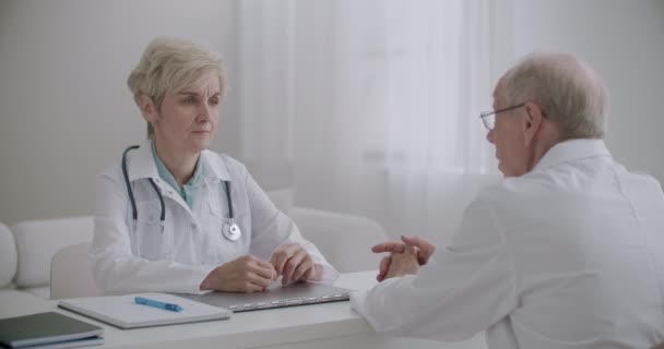 δύο γιατροί μιλούν στο κλινικό γραφείο, συμβουλεύονται ο ένας τον άλλο και συμβουλεύουν, σύμφωνα με ιατρικούς εμπειρογνώμονες και ιατρούς - Πλάνα, βίντεο