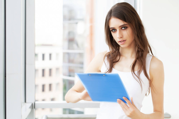 Young beautiful business woman with clipboard in the office. - Foto, Bild