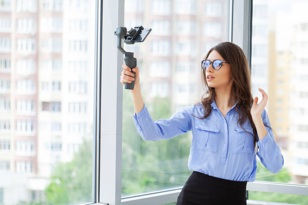 Junge Geschäftsfrau nimmt Videoblog auf Smartphone im Büro auf - Foto, Bild