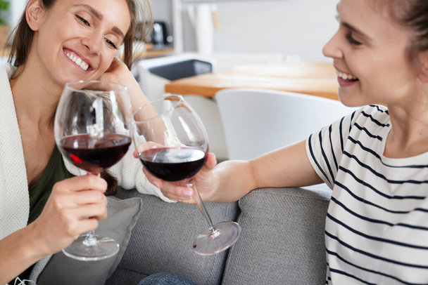 Smiling friends sitting with glass of wine                                 - Foto, imagen