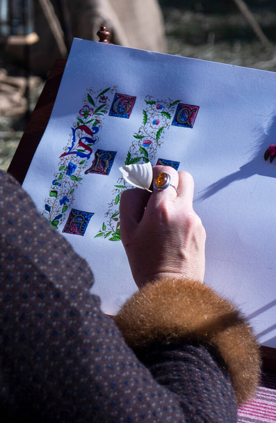 Un artista che usa una penna di piume che dimostra come disegnare lettere illuminate al Abby Medieval Festival, Caboolture, Queensland, Australia. Focus selettivo. - Foto, immagini