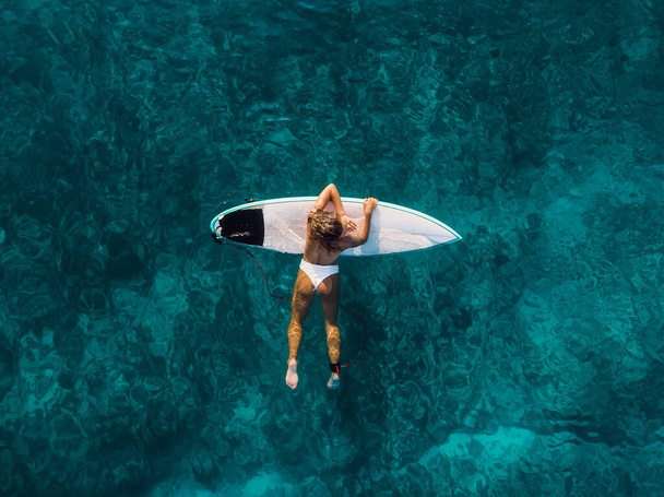 Mujer surfista atractiva en la tabla de surf en el océano azul. Vista aérea - Foto, imagen