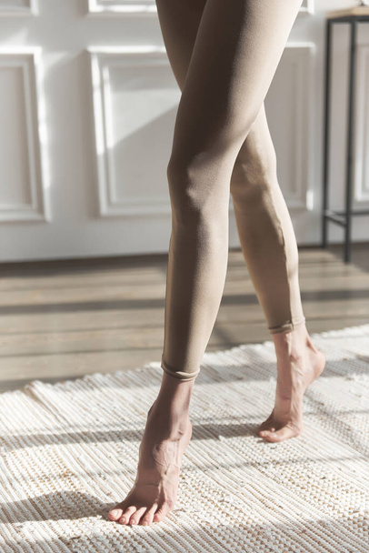 Fit long woman legs in leggings. Close up slim, slender, shapely legs in beige skin-tight sweatpants. Fashion sportswear. Sexy long pumped-up legs fitness model. Sports figure. Posing of feet.Crossfit - Photo, Image