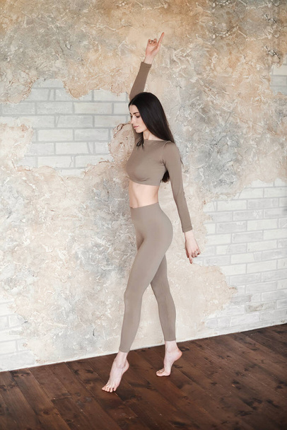Happy woman in grey sportswear, pants. Concept of fashionable sport outfit, vertical photo. Copy space. The concept of sports, healthy lifestyle, fitness, stretching - Φωτογραφία, εικόνα