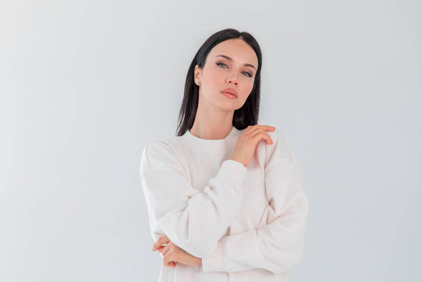 Beautiful adult girl model in white sweater hoody isolated over gray white background. Copy space - Valokuva, kuva
