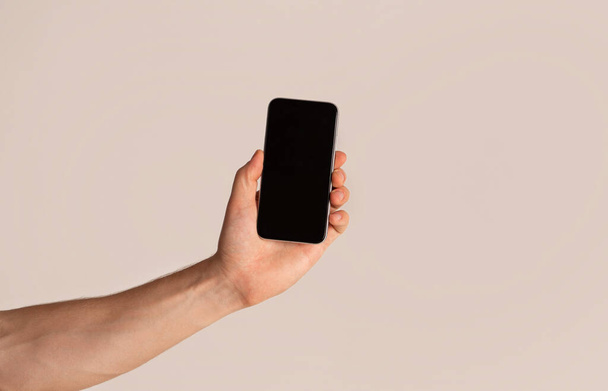 Mężczyzna ręka prezentuje smartfon z pustym ekranem na jasnym tle, makieta do projektowania - Zdjęcie, obraz