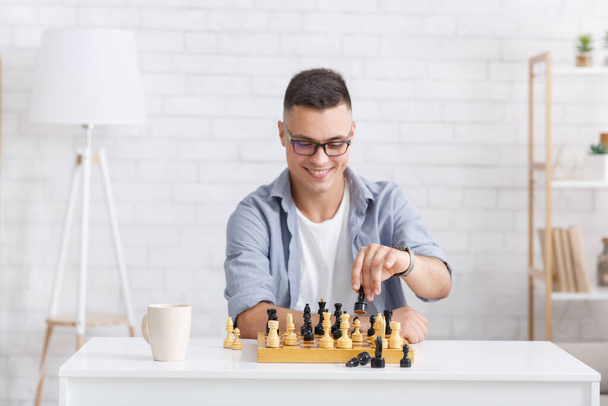 Virtuální soupeř v šachové partii. Usmívající se chlap hraje deskovou hru na online volání - Fotografie, Obrázek