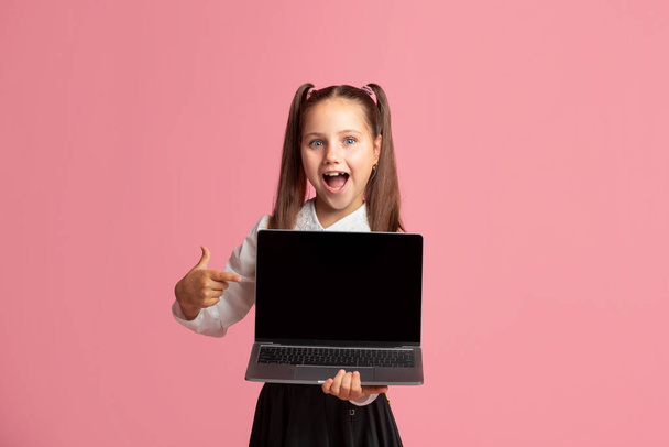 Wow, look there. Happy little girl with open mouth shows at laptop with blank screen - Valokuva, kuva