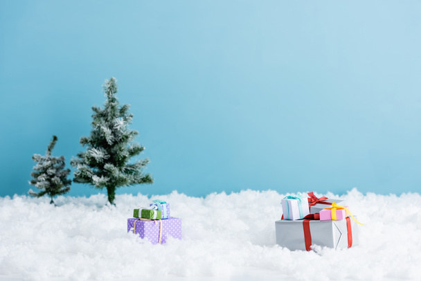 presents on white snow near christmas trees isolated on blue  - Photo, Image