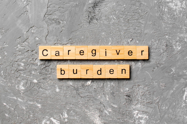 Η λέξη βάρος φροντιστής γραμμένο σε ξύλο μπλοκ. Caregiver κείμενο βάρος στο τραπέζι τσιμέντου για desing σας, έννοια. - Φωτογραφία, εικόνα