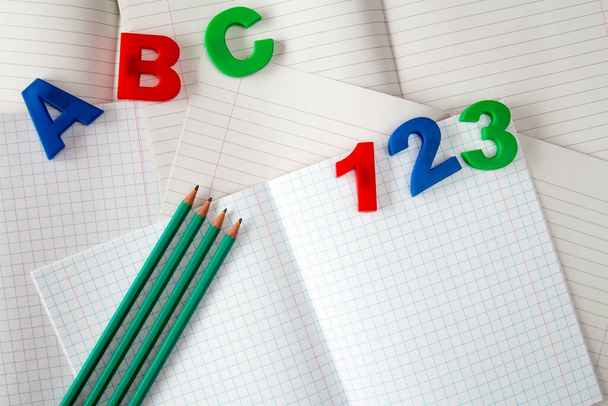 Números y letras de colores en cuadernos de ejercicios con cuatro lápices - Foto, imagen