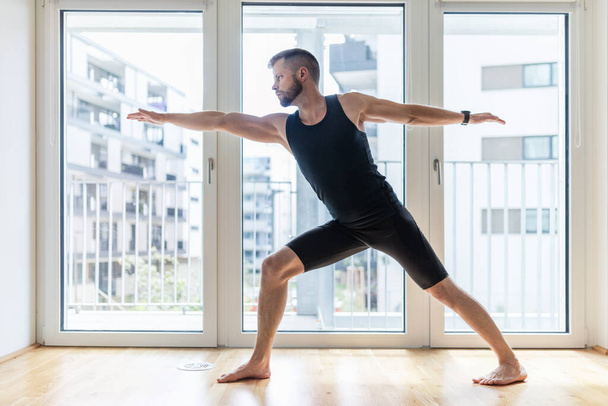 Young handsome man practicing yoga at home - Foto, imagen