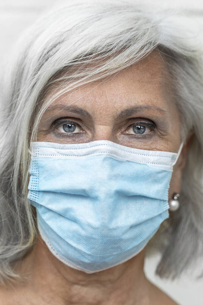 caucasian Gray-haired european woman wearing protective mask and looking at the camera. vertical image - Fotoğraf, Görsel