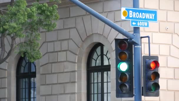 Broadway nazwa ulicy, znak odonimu i sygnalizacji świetlnej na filarze w USA. Skrzyżowanie dróg w centrum miasta. Skrzyżowanie w centralnej dzielnicy biznesowej. Tabliczka z nazwą głównej alei - Materiał filmowy, wideo