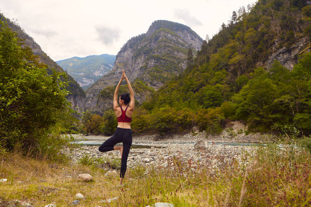 Cours de yoga dans la nature. Une femme fait du yoga dans les montagnes, près d'une rivière de montagne coule. Le concept de faire du sport seul. Exclusion sociale - Photo, image
