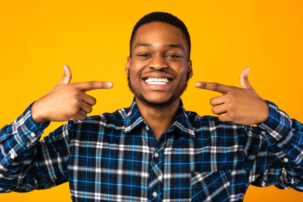 Чорний хлопець вказує пальці на його білі зуби, студійний знімок
 - Фото, зображення