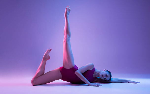 Young and graceful ballet dancer isolated on purple studio background in neon light - Valokuva, kuva