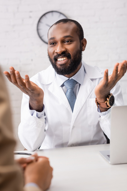 επιλεκτική εστίαση της αφρικανικής Αμερικανός γιατρός gesturing, ενώ μιλάμε για ασθενή στο χώρο εργασίας - Φωτογραφία, εικόνα