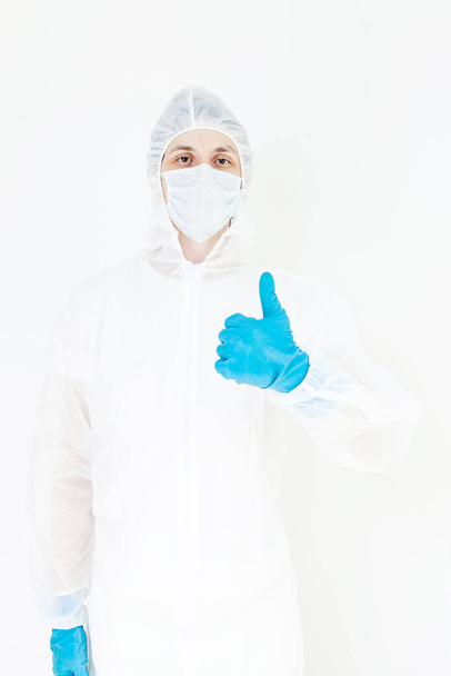 A man in a protective suit gloves and face mask.  Shows the like gesture. Isolated on a white background - Фото, зображення
