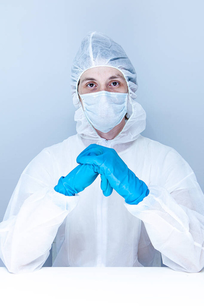 Ένας άντρας με προστατευτική στολή, γάντια και μάσκα προσώπου. Η έννοια της υγειονομικής περίθαλψης. - Φωτογραφία, εικόνα