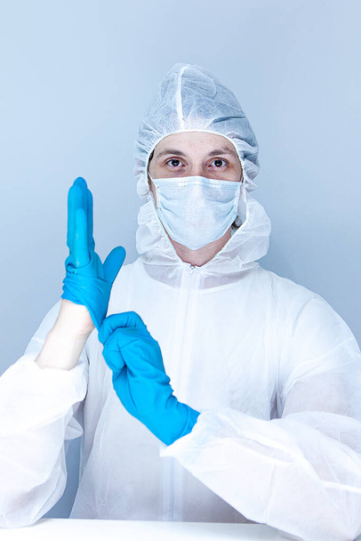 een man in een beschermend pak, handschoenen en gezichtsmasker. Het begrip gezondheidszorg. - Foto, afbeelding