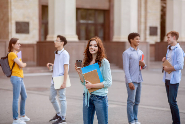 Menina estudante alegre tendo café durante a pausa em pé fora da Universidade - Foto, Imagem