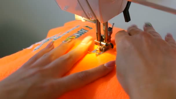 Joven costura de costura de la mano de la mujer cose en una máquina de coser. La aguja y el pie de una máquina de coser con hilo hacen puntadas en la tela - Metraje, vídeo