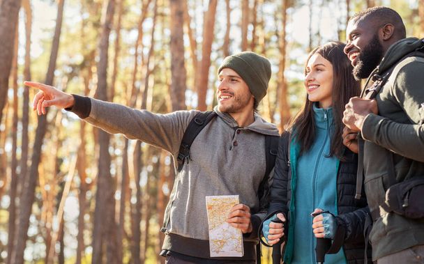 Szczęśliwi turyści znaleźli właściwą drogę, trzymając mapę w lesie - Zdjęcie, obraz