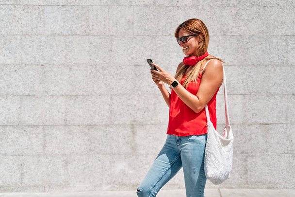 Mujer joven usando su teléfono móvil en la ciudad. Concepto de nuevas tecnologías y redes sociales. - Foto, Imagen