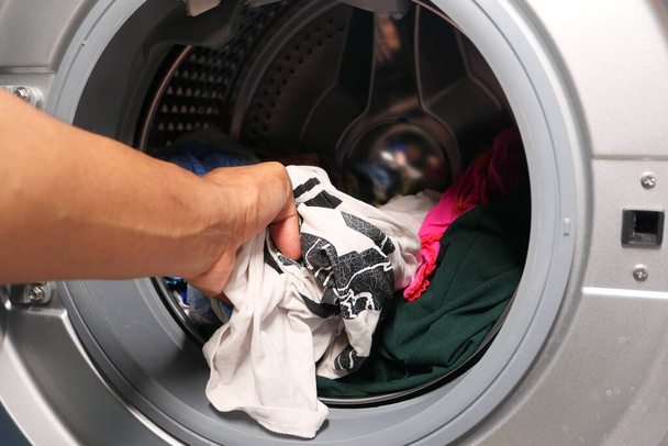  homem colocando camisa na máquina de lavar roupa. - Foto, Imagem