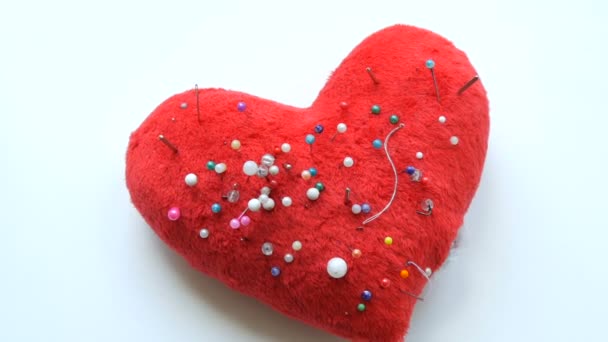 Булавочная подушка в виде мягкого красного сердца, в которой много булавок и иголок для вышивки и шитья застряли в швейной мастерской или ателье - Кадры, видео